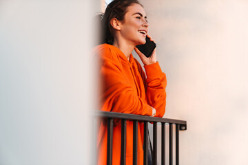 Image of woman talking on cellphone while bending over railing