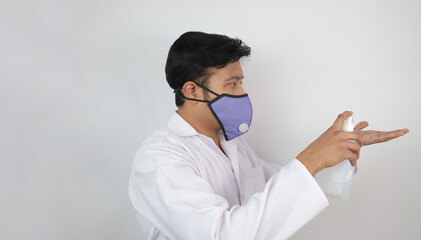 a male doctor in mask and white coat demonstrating use of hand sanitizer. Hand washing protocol