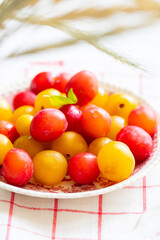 Ripe red and yellow plums on a vintage plate. On light background. Scandinavian style.
