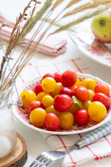 Ripe red and yellow plums and apples on a vintage plate. On light background. Scandinavian style.