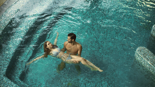 Top view of joyful couple bathing at spa resort. Cheerful couple enjoying pool