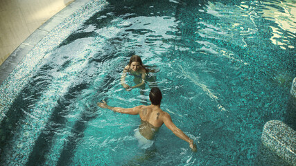 Top view of cheerful couple in pool indoor. Couple having fun in whirlpool bath