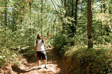 Naklejka na ściany i meble Photo of young traveler standing in middle of forest and pointin