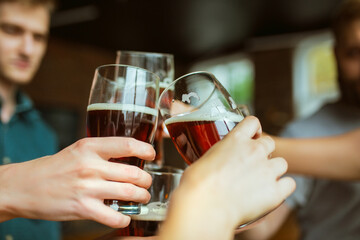 Close up clinking. Young group of friends drinking beer, having fun, laughting and celebrating together. Women and men with beer's glasses. Oktoberfest, friendship, togetherness, happiness concept.