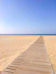 Fototapeta na wymiar Amanecer en la playa con camino de madera.