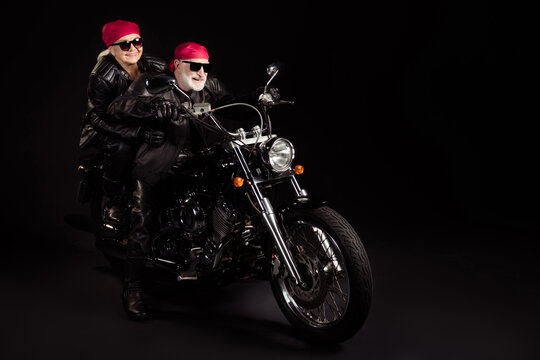 Full length photo of aged bikers grey haired man lady couple drive moto traveling rock festival for pensioners wear rocker leather jacket pants bandana isolated black color background