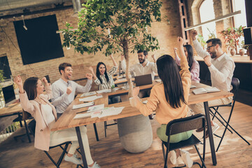 Photo of business people colleagues sit around table celebrate success great anti crisis plan team members professionals raise fists got money save working places office indoors