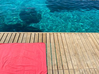 Red beach towel on wooden floor