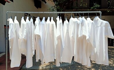 Several white shirts were aired on outdoor iron racks.