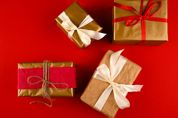 Christmas background with gift boxes wraped in craft paper over red table.