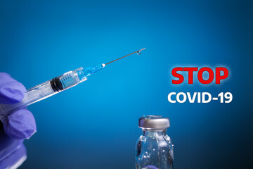 Stop COVID-19. The doctor's hand in medical gloves holds a syringe for injection, and next to the...