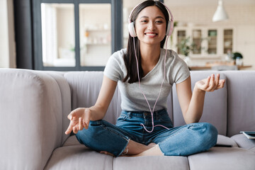 Obraz premium Image of woman listening music with headphones while sitting on sofa