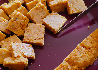 cakes of dal being cut in uniform pieces to cook dhoka r dalna a popular bengali vegeterian recipe.