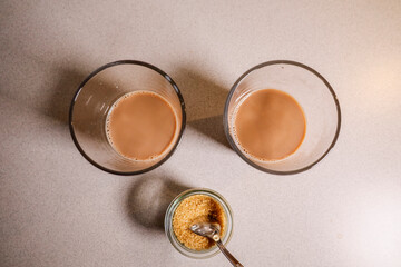 Two cups of fresh cafe au lait and a bowl of sugar.