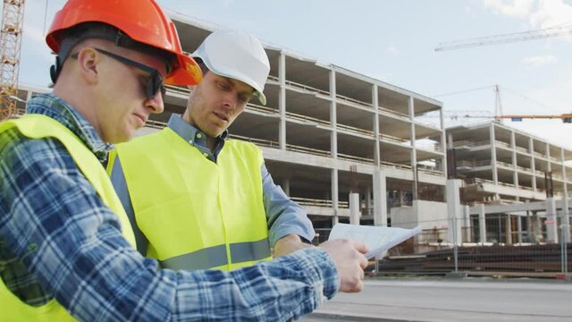 Professional builders standing in front of construction site. Office building and crane background.