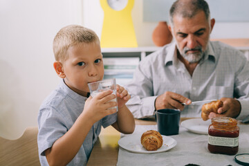 boy holding glass of milk sitting dinning table at home