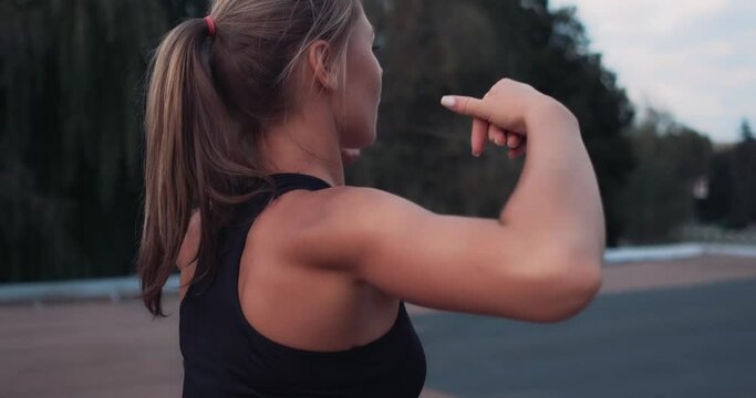 Close up of Athletic Fit Girl in Black Sportswear Doing Warm up Exercises Outdoors, Getting Ready for Workout or Race Competition, Stretching Arms and Back Muscles. Tracking Arc Shot.