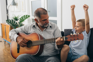grandfather and grandson having fun playing guitar at home