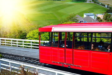 Bright red cable car going down the steep hill on a sunny day. Wellington, New Zealand - Powered by Adobe