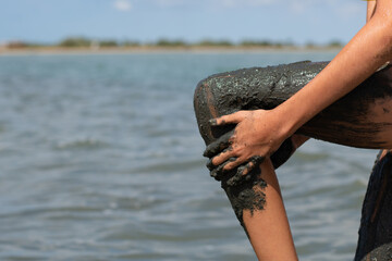 The girl rubs her leg with medicinal black mud from the lake. Healing salt lake in the Crimea.
