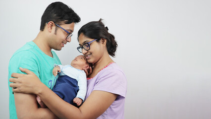 a young man with his wife and newborn kid looking at the baby isolated in white background
