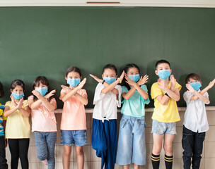 Group of diverse young students wear mask and showing stop sign gesture in classroom