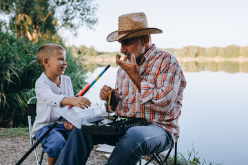 Obraz na płótnie Canvas grandfather and grandson fishing outdoor on the lake