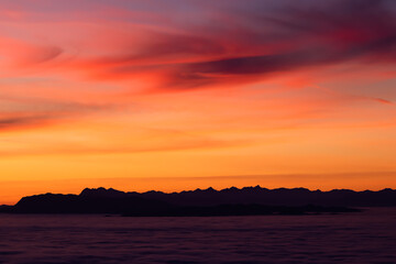 Beautiful orange and red purple sky sunset over the mountains with dense fog in the valley