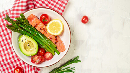 Bowl Buddha. Baked salmon garnished with asparagus and tomatoes with herbs on a light background, top view. space for your text.