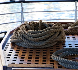 Strong maritime hemp rope coiled up on a polished teak deck.