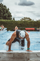 Triathlete climbing out of the pool in a race.