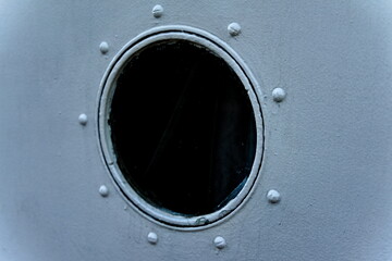 Port hole on a riveted steel ship.