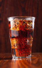 glass of cold cola soft drink with ice on wooden background