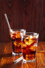 glass of cold cola soft drink with ice on wooden background