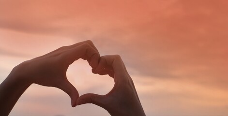 Plakat hand holding a heart on sunset background 