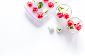 Raspberry and lime in ice cubes on white table top view copy space