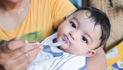 an infant toddler baby boy after weaning eating solid food with spoon