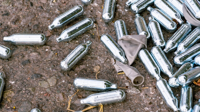 Discarded Nitrous Oxide canisters and grey balloon