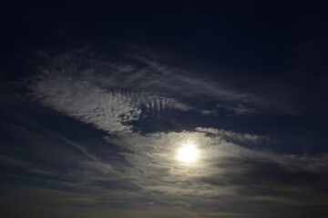 The solar disk is entangled in light cirrus clouds. Typical signs of weather change. Natural...