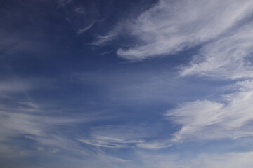 Light cirrus clouds in the deep blue sky. Typical signs of weather change. Natural background for graphic projects.