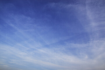 Light cirrus clouds in the deep blue sky. Typical signs of weather change. Natural background for graphic projects.