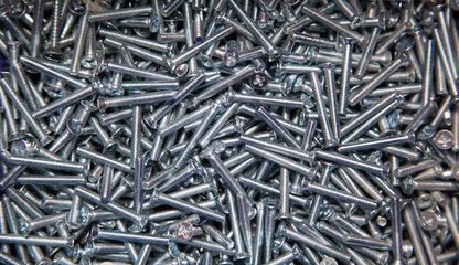 Metal screws of gray color in the mirror. Construction, background, textures, design.