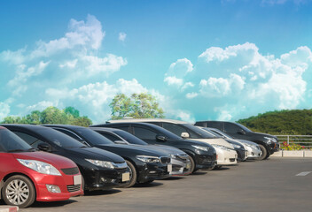Car parked in large asphalt parking lot with white cloud and blue sky background. Outdoor parking...