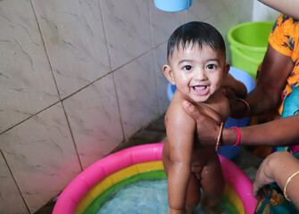 an infant toddler baby boy wet with foam enjoying shower bathing