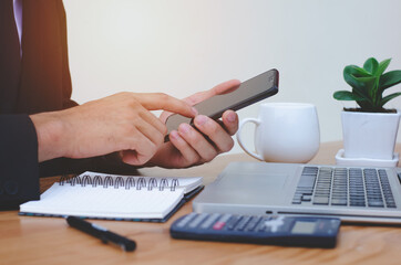 a young man working from home using smart phone and laptop computer man. Side view shot of hands using a smart phone, the man at his workplace.