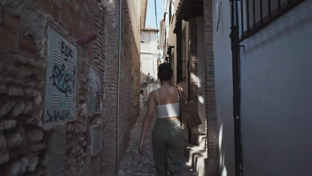 young beautiful woman walking along the streets of Granada with a casual look on the morning
