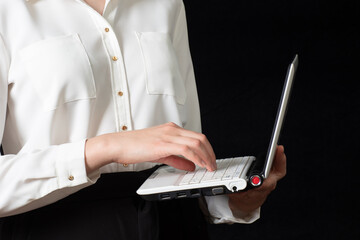 Close-up of a female hand using a laptop computer and touching the screen, isolated on black background