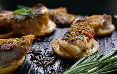 Grilled fish with lemon, herbs and rosemary. Fried fish fillets in a grill pan. Close-up.