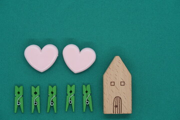 Green and pink paper clips and toy wooden house, symbol of mortgage and real estate purchase