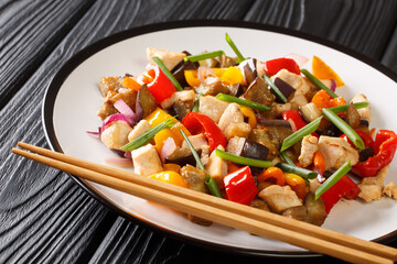 Asian food stir fried chicken with eggplant, pepper and onion in spicy soy sauce close-up in a plate on the table. horizontal